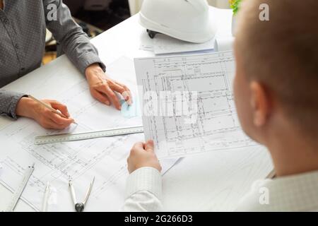 The team of architects is working on the sketches of the blueprints for the project. Engineers create a room design by drawing on paper. Stock Photo