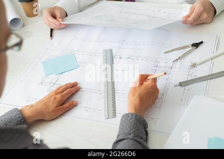 The team of architects is working on the sketches of the blueprints for the project. Engineers create a room design by drawing on paper. Stock Photo