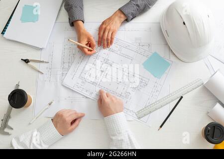 The team of architects is working on the sketches of the blueprints for the project. Engineers create a room design by drawing on paper. Stock Photo