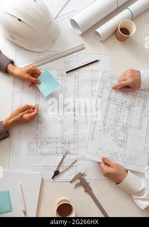 The team of architects is working on the sketches of the blueprints for the project. Engineers create a room design by drawing on paper. Stock Photo