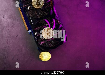 Gold Bitcoin on the video card cooler on a dark background top view. The concept of mining and mining of cryptocurrency, the device of a cryptocurrenc Stock Photo