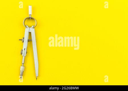 Geometry education concept background with drawing compass on the table, yellow office desk, top view and copy space photo Stock Photo