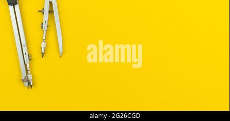 Geometric school instrument and supplies banner background, concept of education, drawing compass on yellow office desk, copy space and top view photo Stock Photo