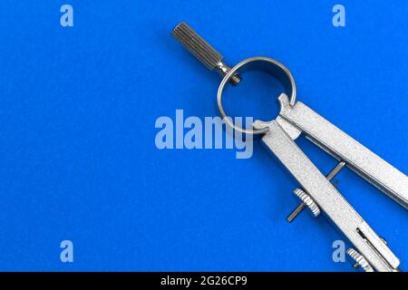Geometry equipment background, drawing compass close-up on the blue table background, copy space photo Stock Photo