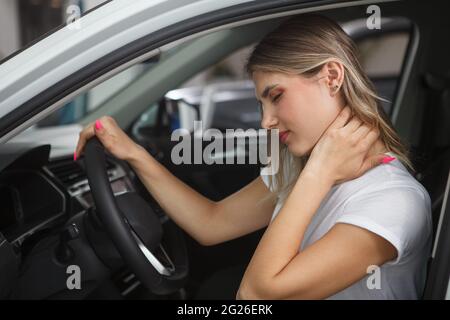 Young woman suffering from neck whiplash, sitting in drivers seat of her car Stock Photo