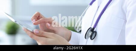 Doctor with stethoscope working on digital tablet closeup Stock Photo