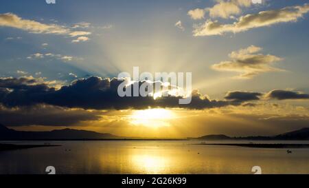 Sun beams shining through gloomy clouds over Lake Elsinore Stock Photo