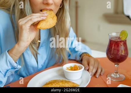 Portrait of girl eating a fried quesadilla in restaurant with prawns and a beverage in a a restaurant Stock Photo