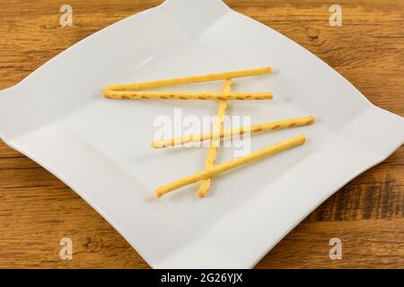 Buttered corn flavored pretzel sticks on white snack plate on table Stock Photo