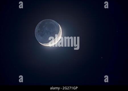 Earthshine lights the dark side of the moon on the waxing crescent moon. Stock Photo