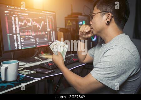 work from the home lifestyle of young trader holding USD dollar trading money exchange  with crypto blockchain online Stock Photo
