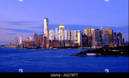 USA; NEW YORK CITY; LOWER MANHATTAN SKYLINE AT DUSK; FREEDOM TOWER; GOVERNOR'S ISLAND IN FOREGROUND Stock Photo