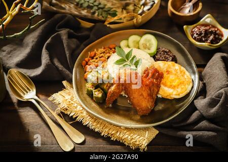 Nasi Lemak. Malay rice dish of fragrant rice with fried chicken, chili paste, peanuts, anchovies, egg. Stock Photo