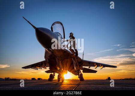 Pilot climbs into a Bulgarian Air Force MiG-29 during sunset at Graf Ignatievo Air Base, Bulgaria. Stock Photo