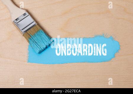 ONBOARDING. Paint brush with blue paint on a wooden surface. Stock Photo