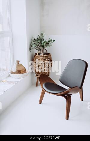 Modern armchair in black leather and wood in a white loft interior. Designer chair. Soft selective focus. Stock Photo