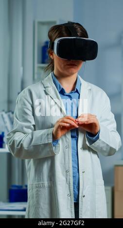 Advanced neurological scientist using medical inovation in lab wearing virtual reality glasses, gesticulating. Team of researchers working with equipment device, future, medicine, healthcare, vision, simulator Stock Photo