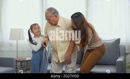 Asian family, Daughter and granddaughter take care support grandfather who is suffering from knee pain Got walking outside to take a walk And grandpa Stock Photo