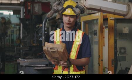 Asian engineering man check and control welding robotics automatic arms machine for automated programming indoors welding manufacturing industrial, Stock Photo