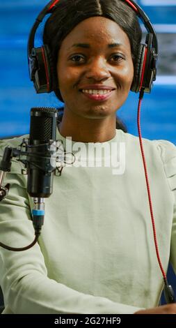Portrait of african smiling blogger looking at camera before starting live video from home studio podcast. Content creator vlogger woman recording brodcast streaming online content for social media Stock Photo