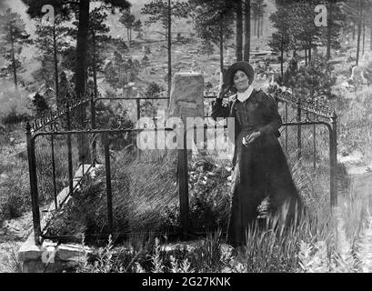Calamity Jane standing next to Wild Bill Hickok's grave in Deadwood, South Dakota.