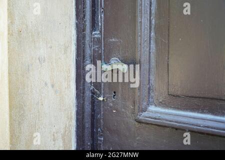 Old unused wooden door with a metal door handle. Cobwebs at the entrance. Stock Photo