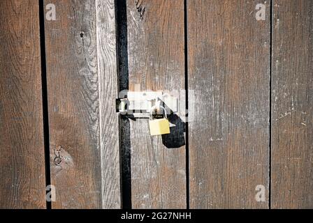 Old weathered wall of a barn with a simple lock. Brown wooden background with a locked door. Stock Photo