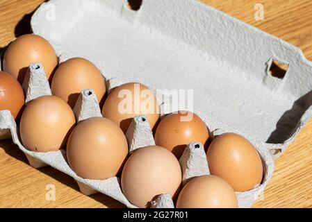 Fresh chicken eggs background. Brown eggs in craft carton pack on hay at rustic wood table.Top view. Natural healthy organic food.Chicken eggs in cart Stock Photo