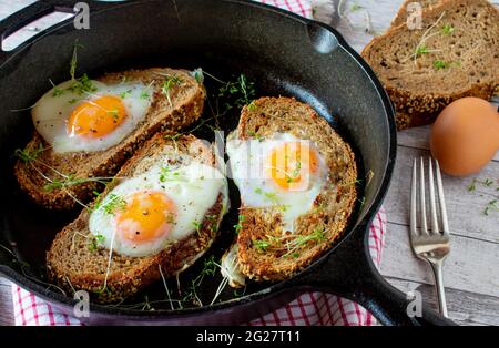 Egg in a whole served in cast iron pan on rustic and wooden table background Stock Photo