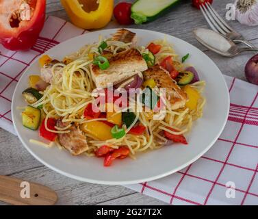 A plate of gluten free pasta dish with fish and vegetables on rustic and wooden table background Stock Photo