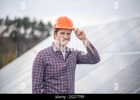 Man in plaid shirt touching and helmet Stock Photo