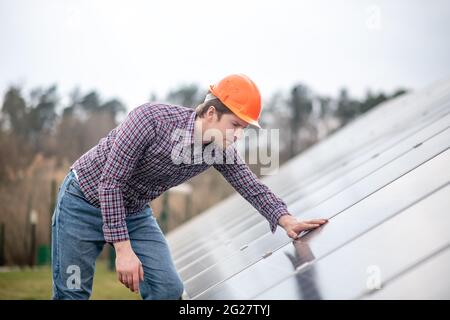 Man in helmet looking at surface of building structure Stock Photo