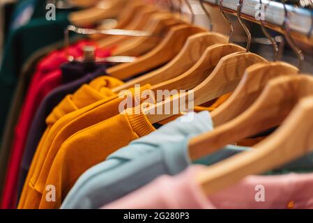 Multicolored cotton sweaters hang on hangers in the store. Stock Photo