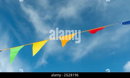 Colored triangles on a ribbon soar in the air against the sky. Stock Photo