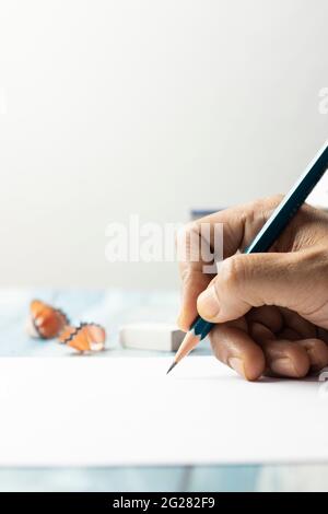 Close up view of hand and pencil writing on paper and white background Stock Photo