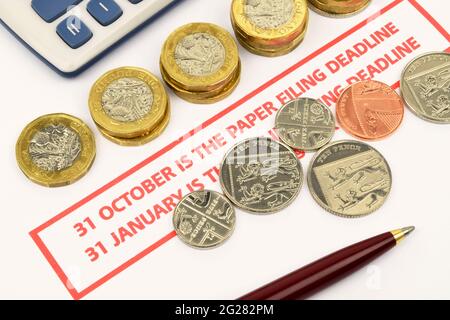 United Kingdom tax return paper filing deadline reminder. A still life  including a calculator, coins and pen. Stock Photo