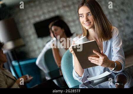 Happy woman manager holding tablet and sitting in cafe Stock Photo