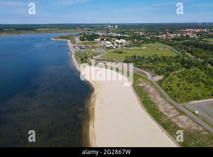 09 June 2021, Brandenburg, Großräschen: The bright sand of the city beach at Großräschener See shines in the morning sun (aerial view with a drone). The newly created beach gives a little Caribbean flair when you look at it. According to the Lausitzer und Mitteldeutschen Bergbau-Verwaltungsgesellschaft mbH (LMBV), the beach and lake are still closed for use. The water level in Lake Großräschen, formerly the Meuro open-cast lignite mine, has not yet reached its final level. Where lignite mining once dominated the landscape, new water paradises with around 14,000 hectares of water are currently Stock Photo