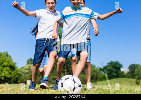 Happy family playing football in park in summer Stock Photo