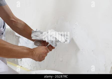 Hands man plasterer construction worker at work with trowel, plastering a wall, closeup Stock Photo