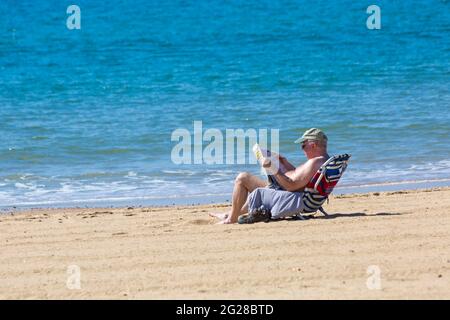 Bournemouth, Dorset UK. 9th June 2021. UK weather: hot and sunny morning at Bournemouth beaches, as sunseekers head to the seaside to enjoy the sunshine. Man reading the Daily Mail newspaper.   Credit: Carolyn Jenkins/Alamy Live News Stock Photo