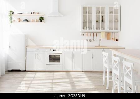 Interior of modern sunny kitchen in Scandinavian style apartment. Light kitchen furniture with utensils Stock Photo