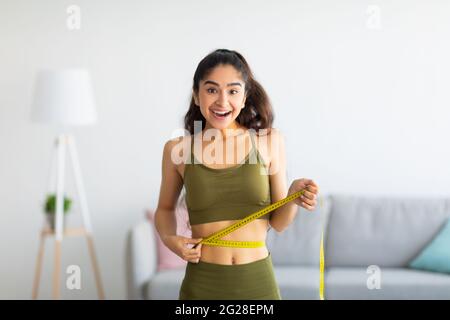 Woman measuring her waist with centimeter tape at home Stock Photo - Alamy