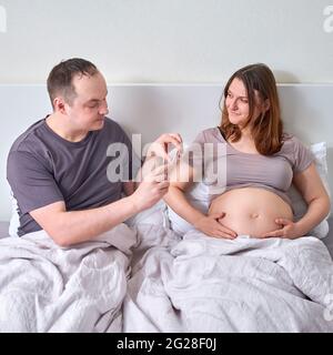 Husband takes video and photo of pregnant wife belly on mobile phone Stock Photo