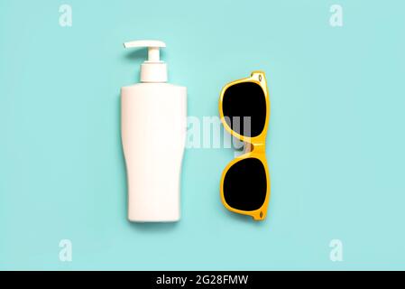 Summer holiday concept.Top view of yellow sunglasses and bottle of sunscreen on a blue background Stock Photo