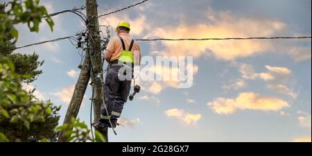 electrical lineman working on electric pole. electrician at work. banner copy space Stock Photo