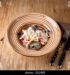 Seafood pasta - Spaghetti with clams, prawns, sea scallops. Italian food. On a wooden background. photo for the menu. Stock Photo