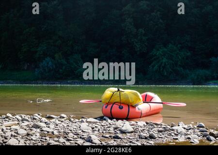 Orange packraft rubber boat with backpack on a river. Packrafting. Active lifestile concept Stock Photo