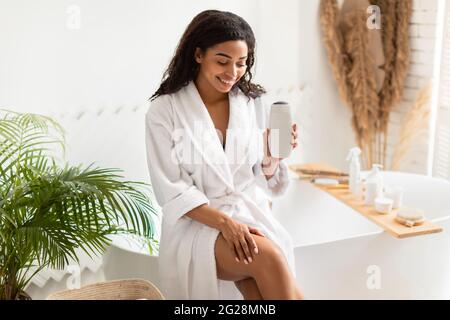Black Lady Holding Shower Gel Sitting On Bathtub In Bathroom Stock Photo