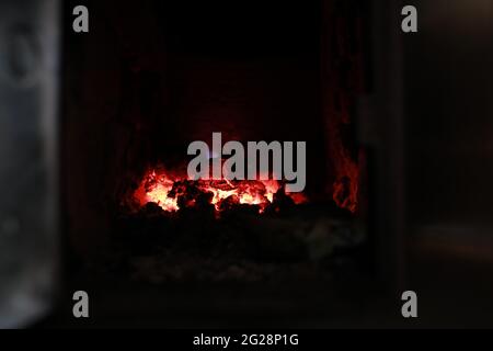 heated stove in the house with red coals and fire Stock Photo